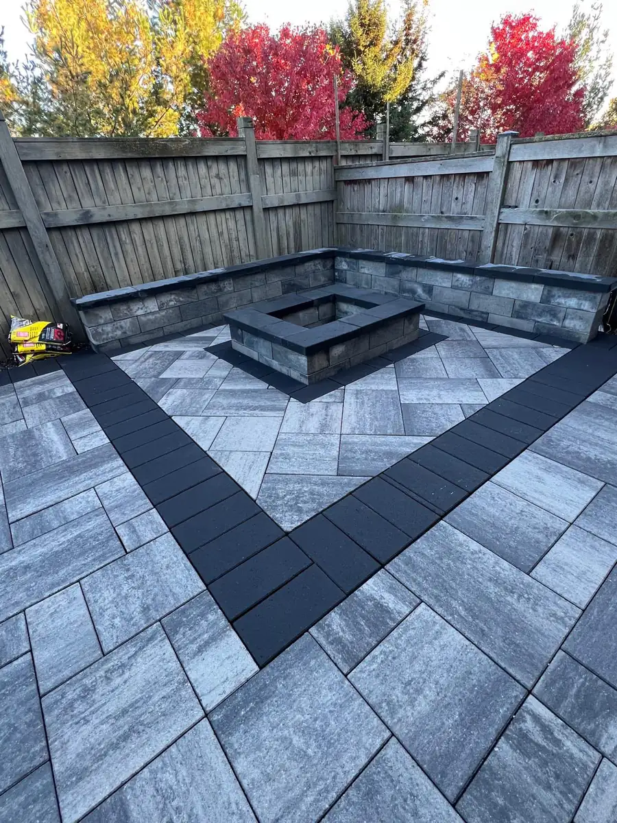 Paver patio with a stacked-stone seat wall and fire pit amid autumn colour