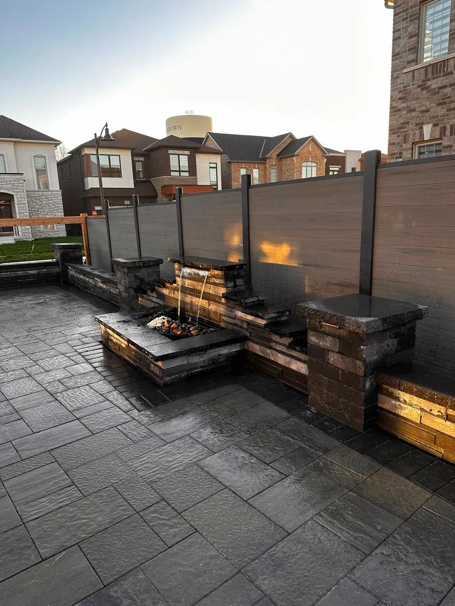 Modern stone fire-and-water feature against a slat privacy fence