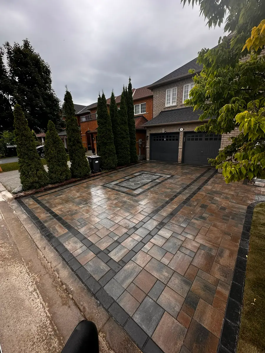 Paver driveway with a central medallion and manicured hedging