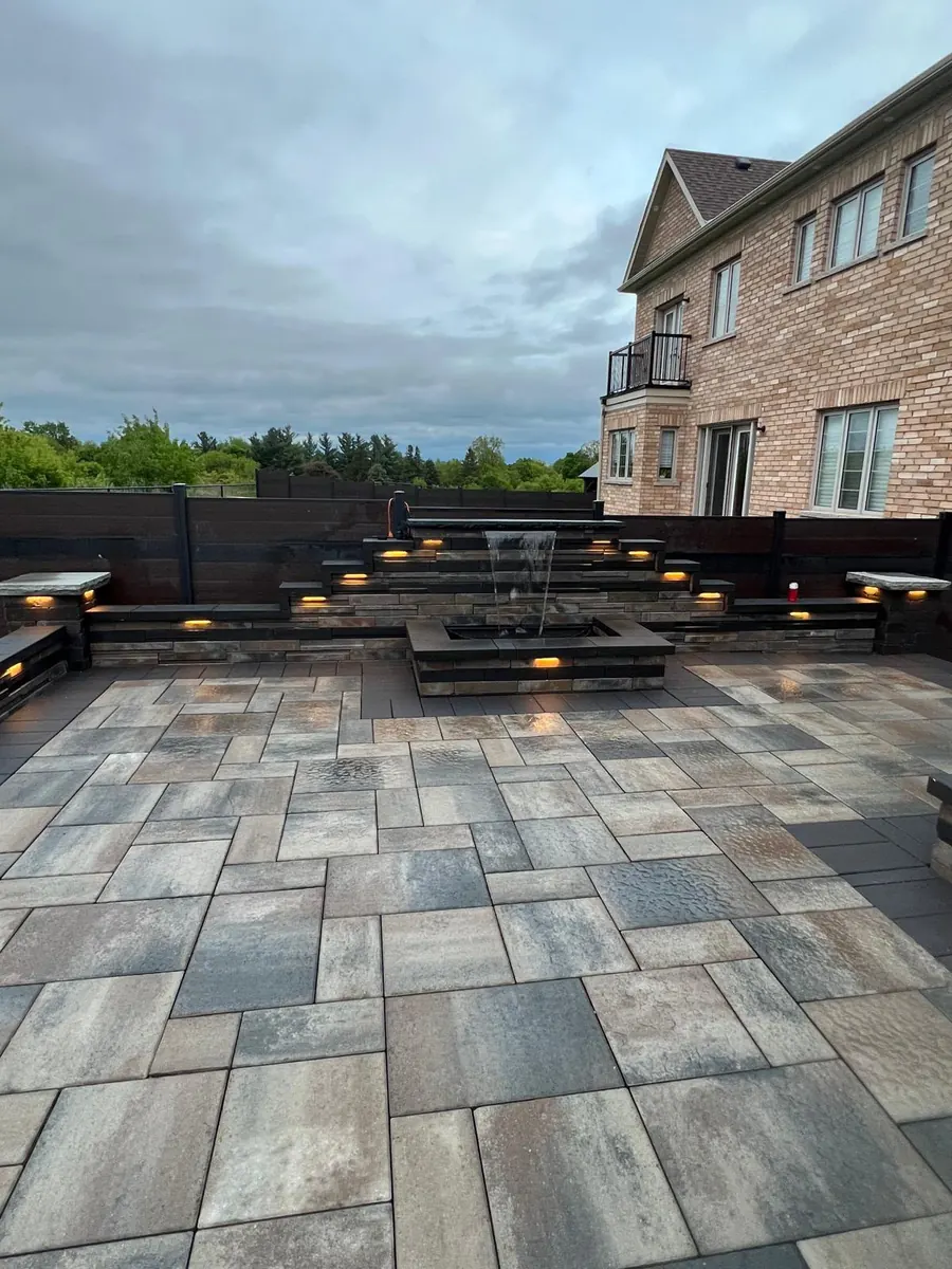 Paver patio with a tiered water fountain feature at dusk