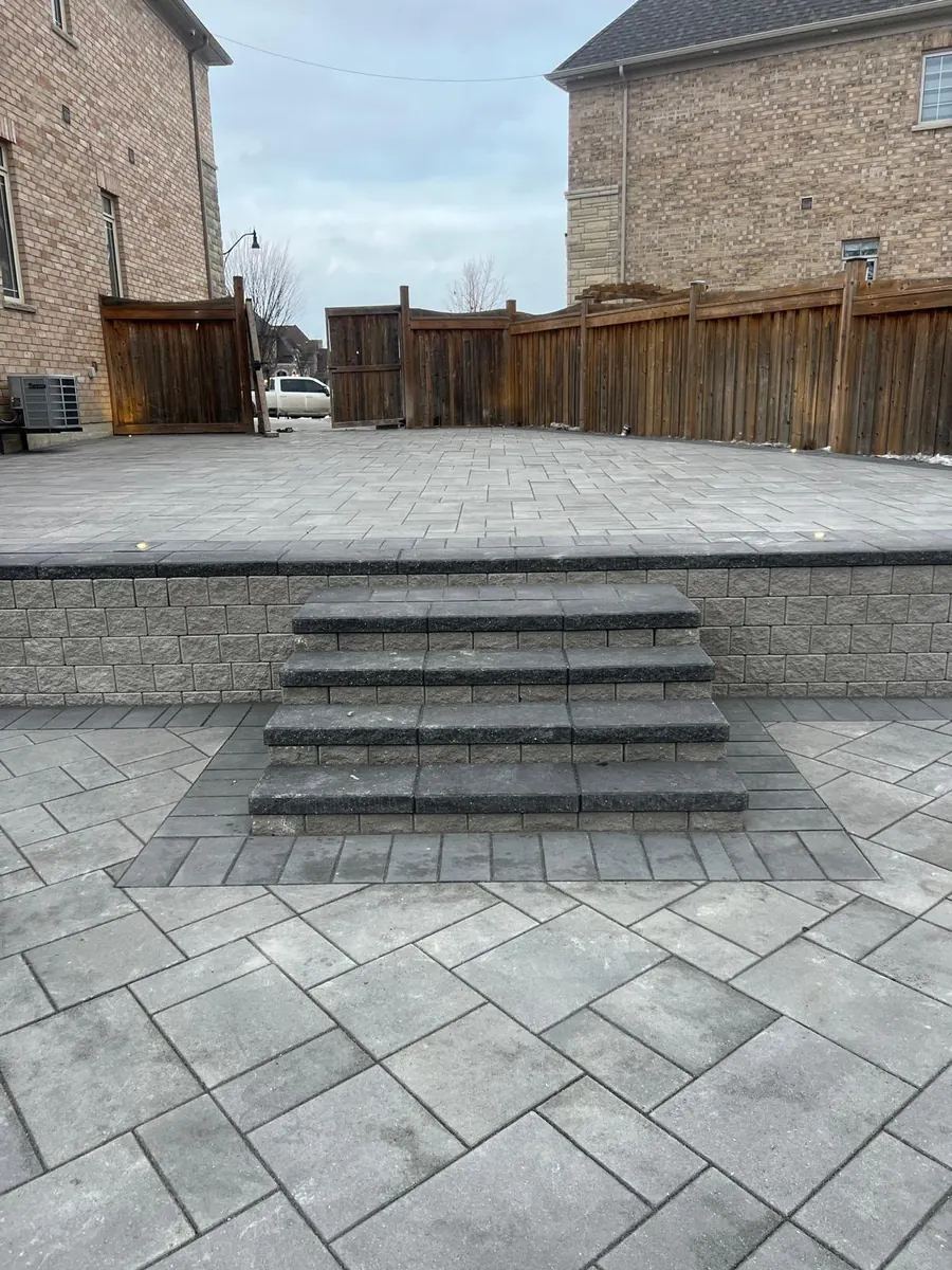 Raised paver patio with a block retaining wall and built-in steps