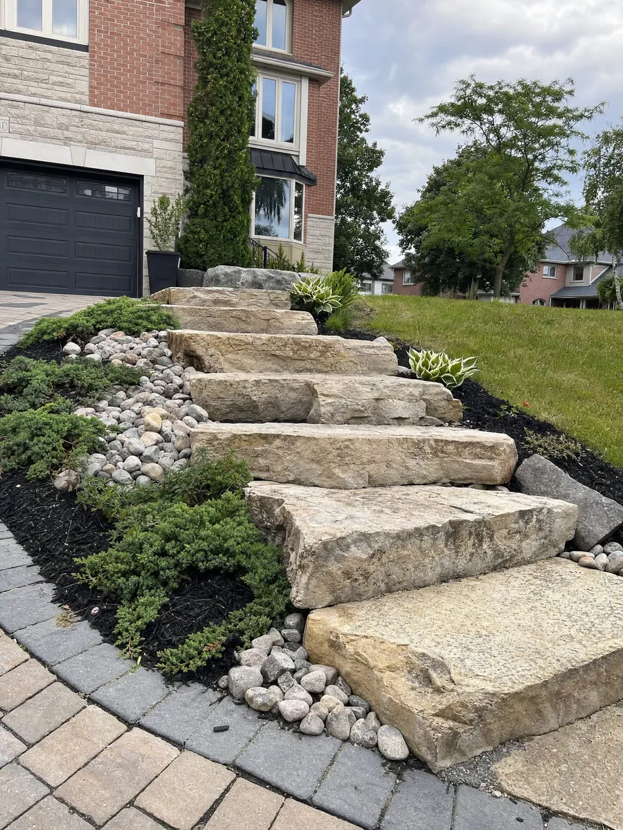 Armour stone garden steps and accent boulders on a sloped front yard