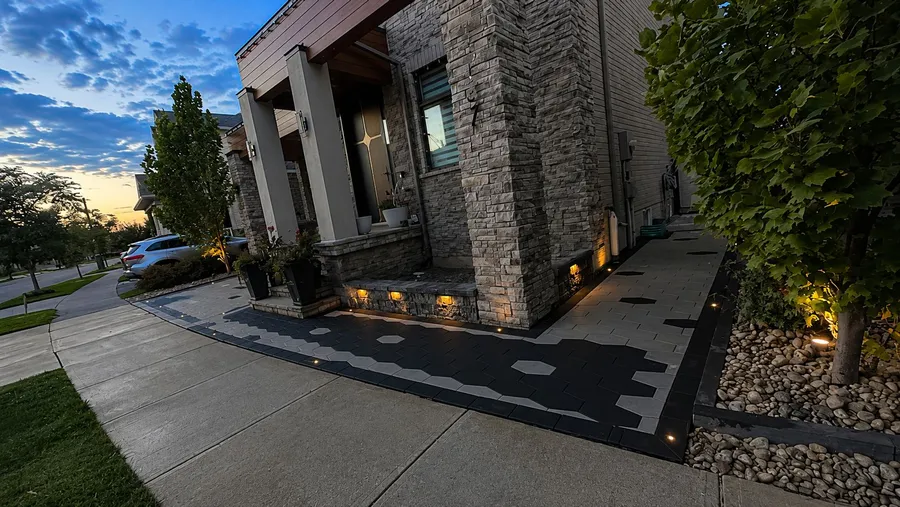 Front entrance courtyard with a hexagon paver driveway, stone pillars and river-rock beds